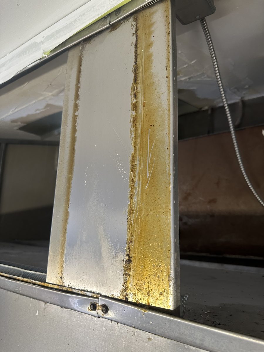 Residential kitchen range hood with grease buildup before cleaning